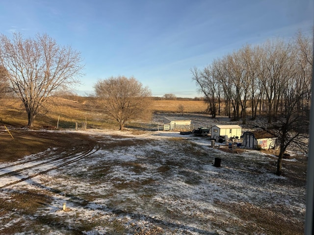 view of yard featuring an outdoor structure, a rural view, and a shed