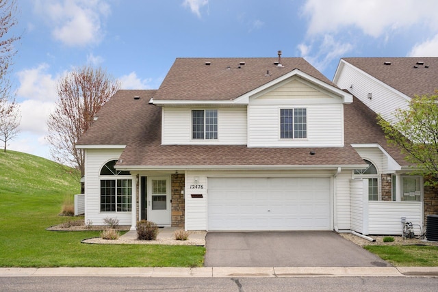 traditional-style home with driveway, a shingled roof, a garage, and stone siding