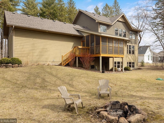 rear view of property with a sunroom, a lawn, stairway, and a fire pit