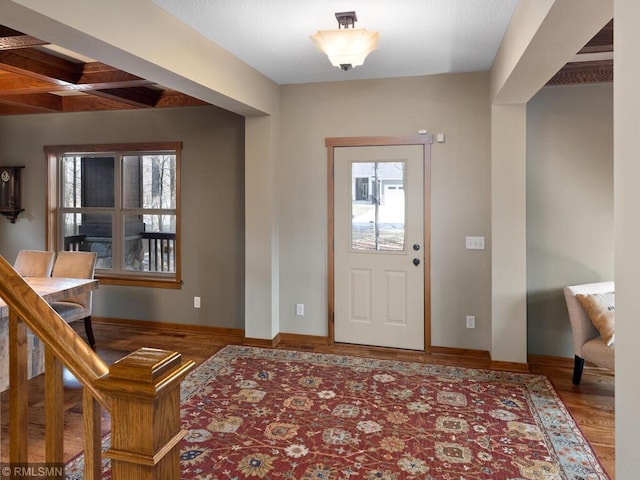foyer entrance featuring wood finished floors, beamed ceiling, and baseboards
