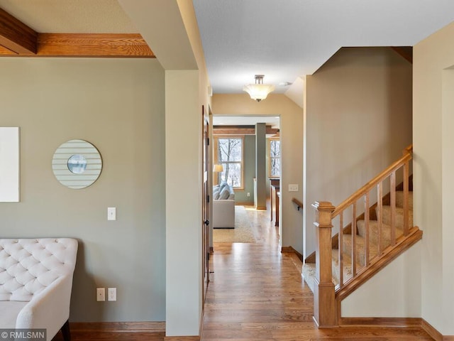 hallway with wood finished floors, baseboards, and stairs