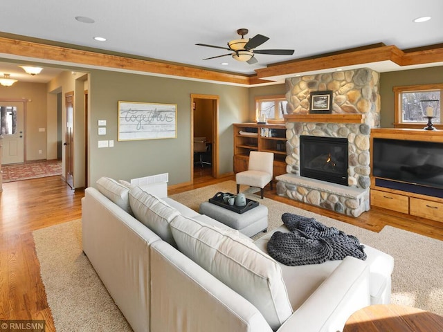 living area with ceiling fan, baseboards, recessed lighting, wood finished floors, and a stone fireplace