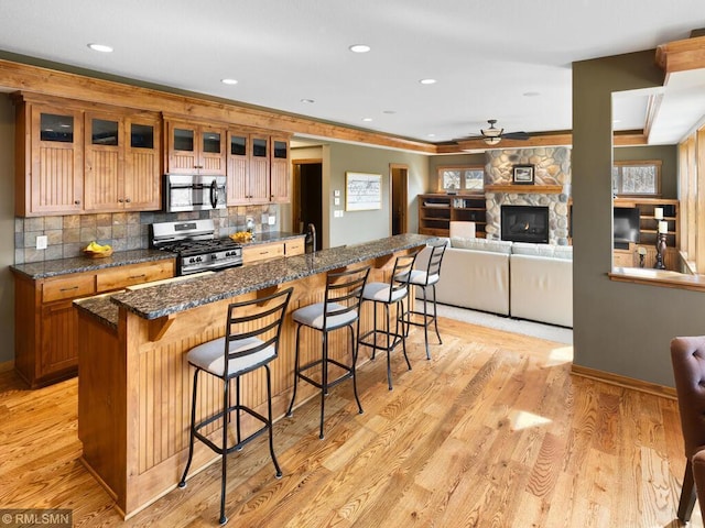 kitchen featuring tasteful backsplash, ceiling fan, a breakfast bar, stainless steel appliances, and a center island with sink