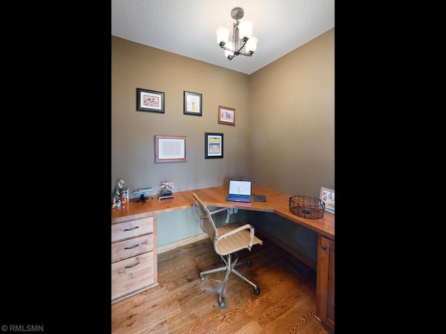 home office with wood finished floors, a notable chandelier, and built in desk