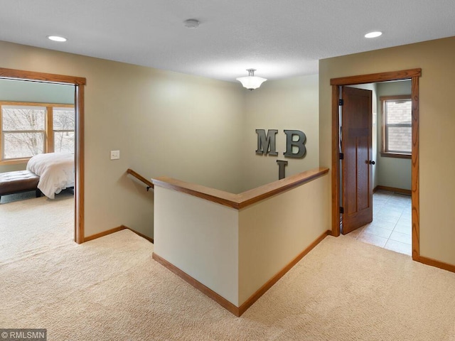 corridor with recessed lighting, an upstairs landing, light colored carpet, and baseboards