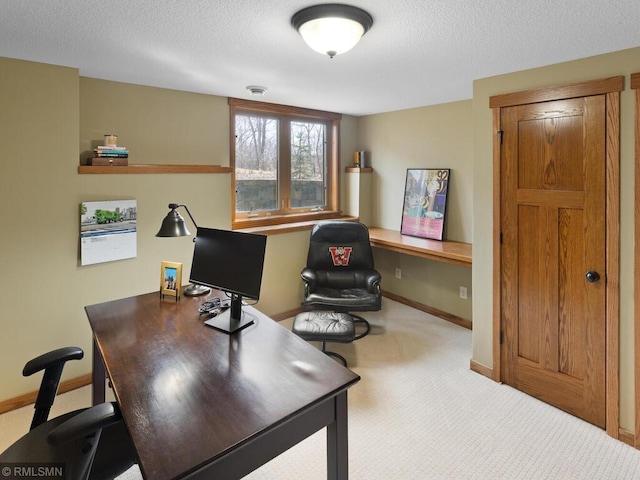 carpeted home office featuring a textured ceiling and baseboards