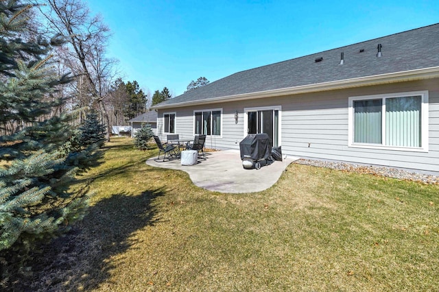 back of house featuring a patio area, a lawn, and a shingled roof