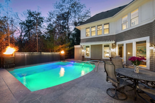 pool at dusk featuring a patio and a fenced in pool