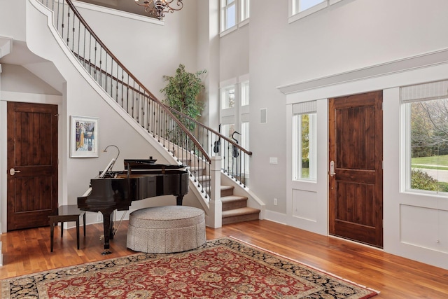 entryway featuring a wealth of natural light, stairs, a high ceiling, and wood finished floors