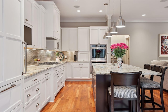 kitchen with tasteful backsplash, a kitchen breakfast bar, crown molding, white cabinets, and stainless steel appliances