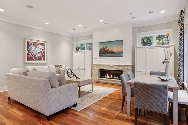 living area featuring crown molding, wood finished floors, a fireplace, and recessed lighting