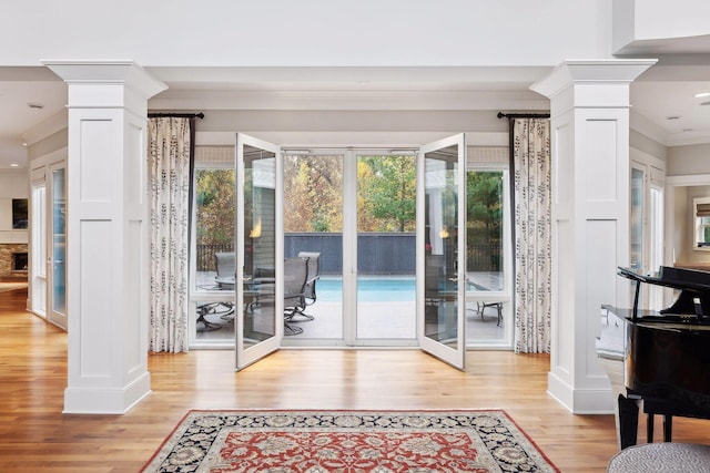 doorway featuring light wood-type flooring, french doors, ornate columns, and ornamental molding