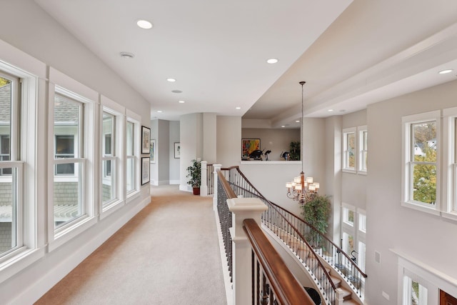 corridor with baseboards, a notable chandelier, an upstairs landing, recessed lighting, and light carpet