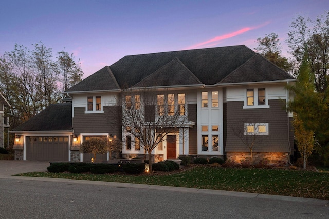 view of front of property featuring an attached garage, driveway, and stone siding
