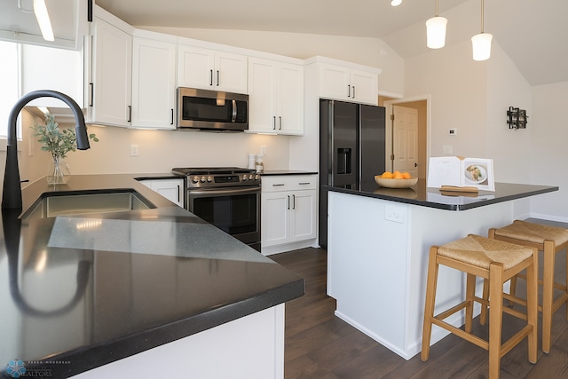 6730 70th Ave S, Horace, ND 58047 - kitchen featuring appliances with stainless steel finishes, dark countertops, vaulted ceiling, dark wood-style flooring, and white cabinetry
