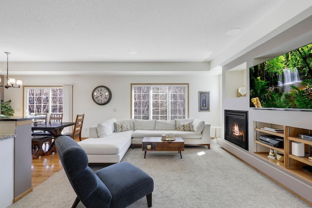 2923 124th Cir NE, Blaine, MN 55449 - carpeted living room featuring a chandelier, a glass covered fireplace, and a textured ceiling