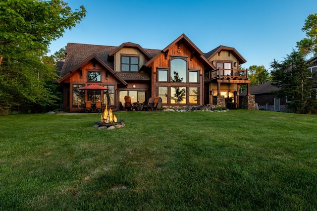 rear view of house with a lawn and a fire pit