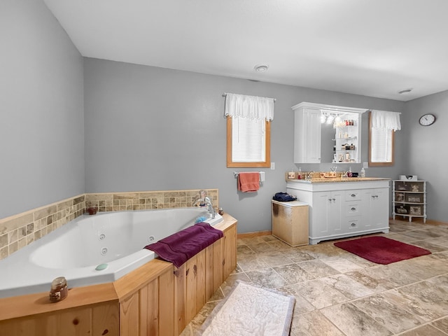 4886 Feelinrite Ln NW, Eckles Twp, MN 56601 - bathroom featuring a jetted tub, vanity, stone finish flooring, and baseboards