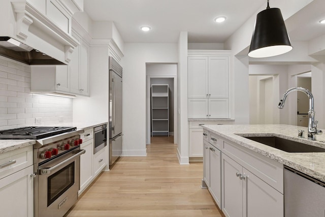 222 Ferndale Rd S Unit 207, Wayzata, MN 55391 - kitchen featuring high end appliances, exhaust hood, light wood-style flooring, white cabinets, and decorative backsplash