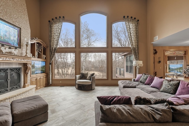 living area with a towering ceiling, a glass covered fireplace, and visible vents