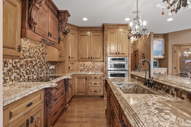 kitchen with light wood-style flooring, tasteful backsplash, a chandelier, a sink, and stainless steel double oven