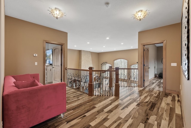 hallway with recessed lighting, an upstairs landing, and wood finished floors