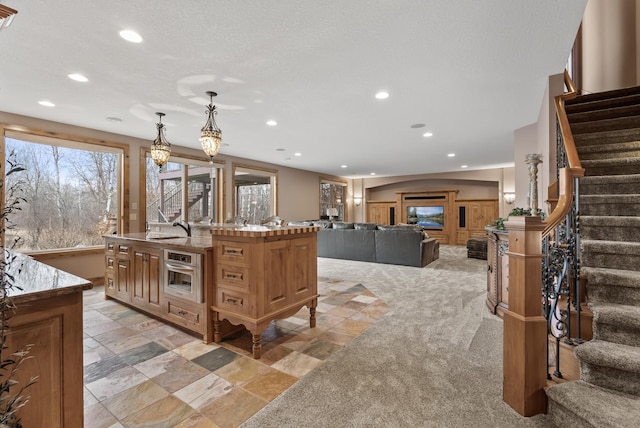 kitchen with a sink, oven, recessed lighting, and an island with sink