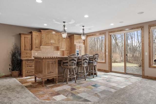 kitchen featuring recessed lighting, stone tile floors, baseboards, and backsplash