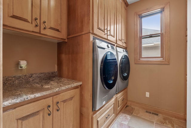 washroom with separate washer and dryer, visible vents, baseboards, and cabinet space