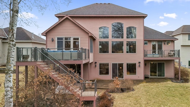 back of house featuring a shingled roof, stairway, and a lawn
