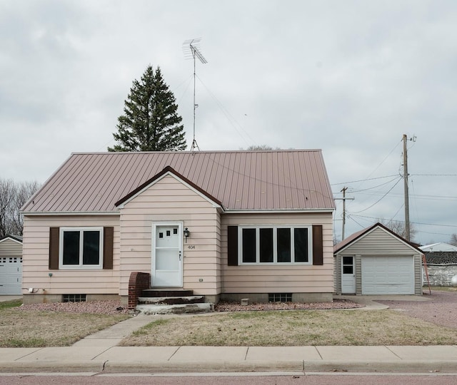 bungalow-style home featuring entry steps, an outbuilding, metal roof, and a detached garage