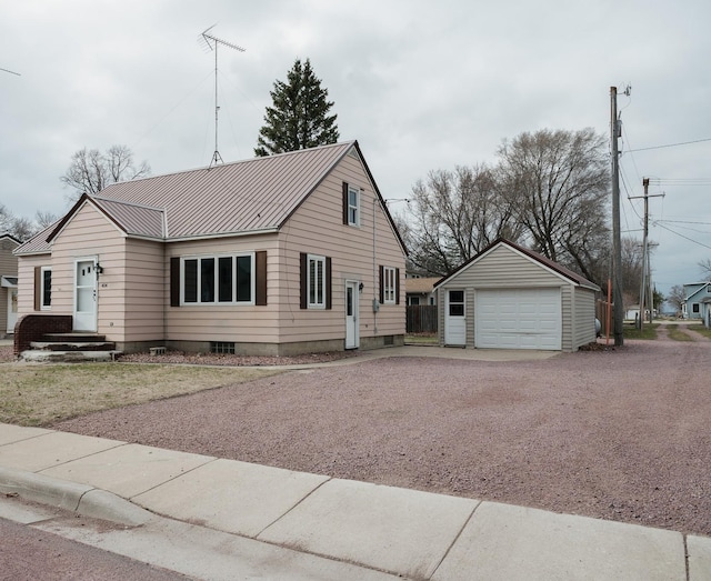 view of front of house with a garage, gravel driveway, metal roof, and an outbuilding