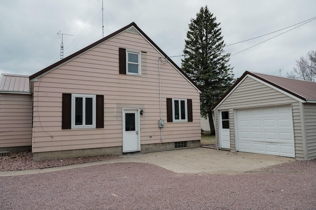 rear view of house featuring driveway, a garage, and an outdoor structure