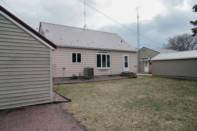 back of property with metal roof, central AC, and a lawn