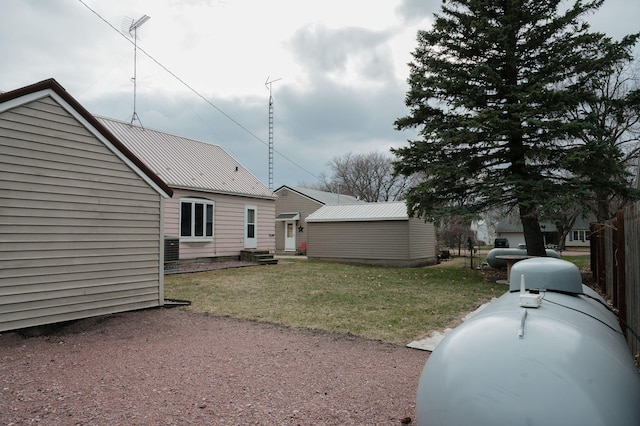 exterior space with cooling unit, entry steps, a yard, metal roof, and fence