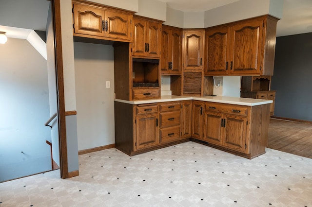 kitchen with brown cabinetry, baseboards, and light floors