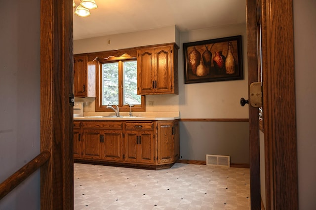kitchen featuring brown cabinets, a sink, visible vents, and light floors