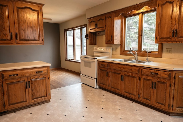 kitchen with a sink, light floors, electric stove, and brown cabinets