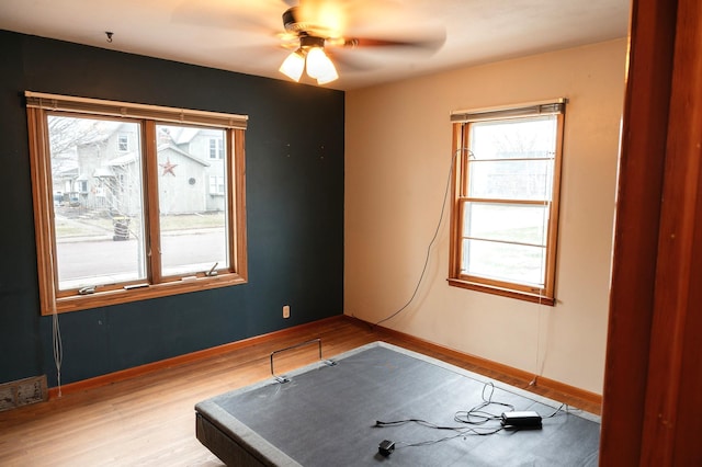 empty room with baseboards, visible vents, light wood-type flooring, and a ceiling fan