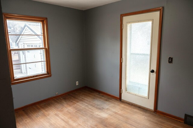 spare room featuring light wood-type flooring, visible vents, and plenty of natural light
