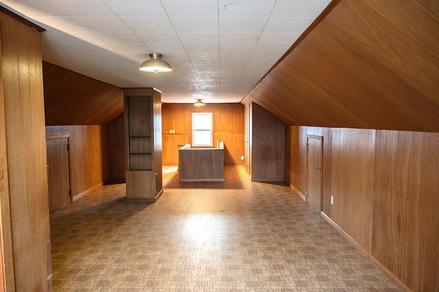 additional living space featuring wood walls, tile patterned floors, baseboards, and vaulted ceiling