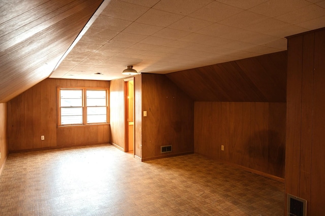 bonus room featuring wooden walls, visible vents, and vaulted ceiling