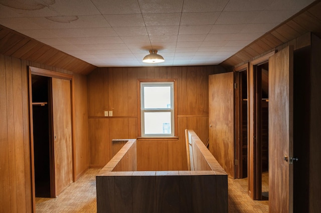 interior space featuring wooden walls, lofted ceiling, and an upstairs landing