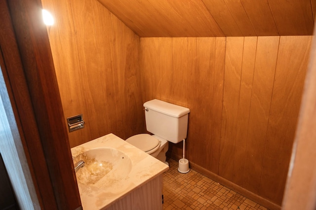 half bathroom with wooden walls, vanity, wood ceiling, and toilet