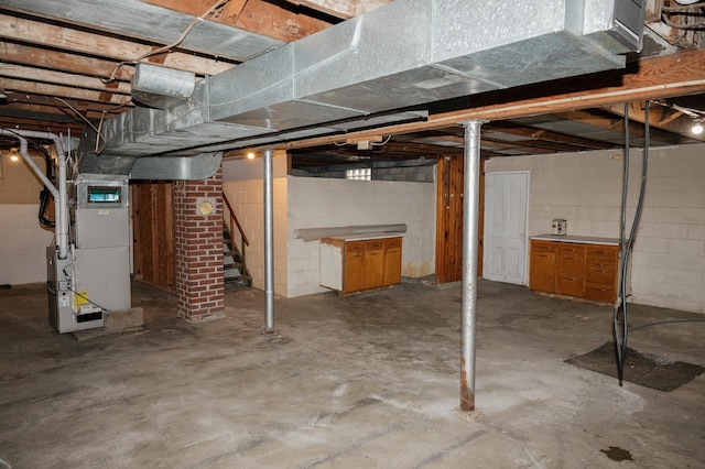unfinished basement featuring stairs and heating unit