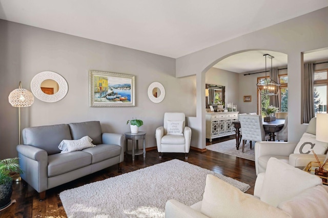 living room with baseboards, arched walkways, and wood finished floors