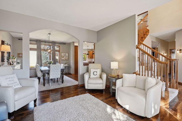 living room with stairs, arched walkways, baseboards, and dark wood finished floors