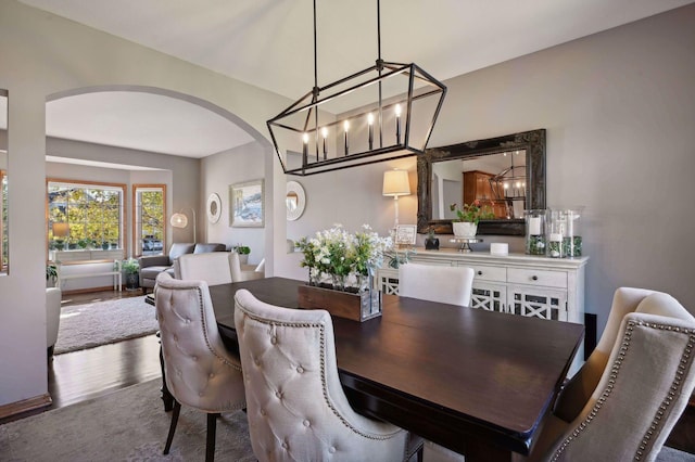 dining area with arched walkways and wood finished floors