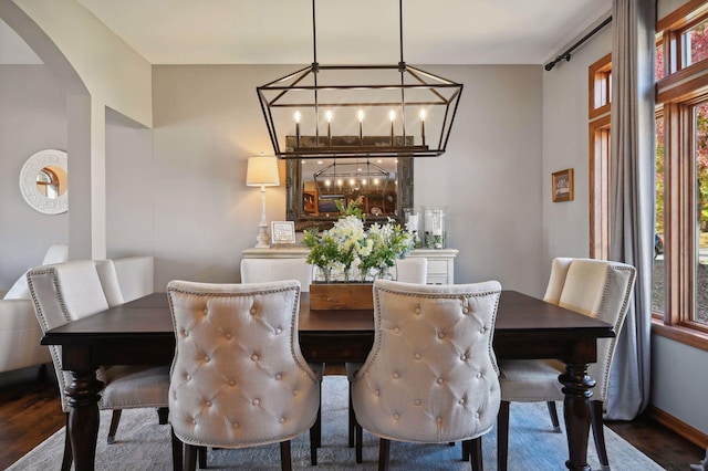 dining area featuring baseboards, a notable chandelier, dark wood finished floors, and arched walkways