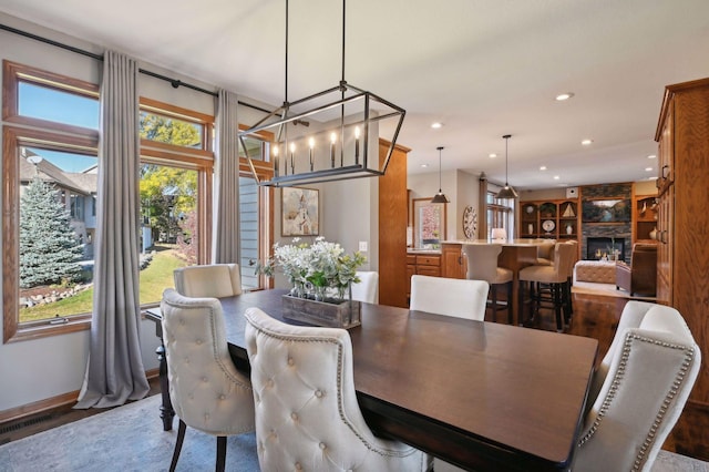 dining area featuring a stone fireplace, dark wood-style flooring, plenty of natural light, and recessed lighting